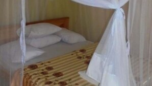 Una habitación con cama, cortinas blancas y mosquitero.