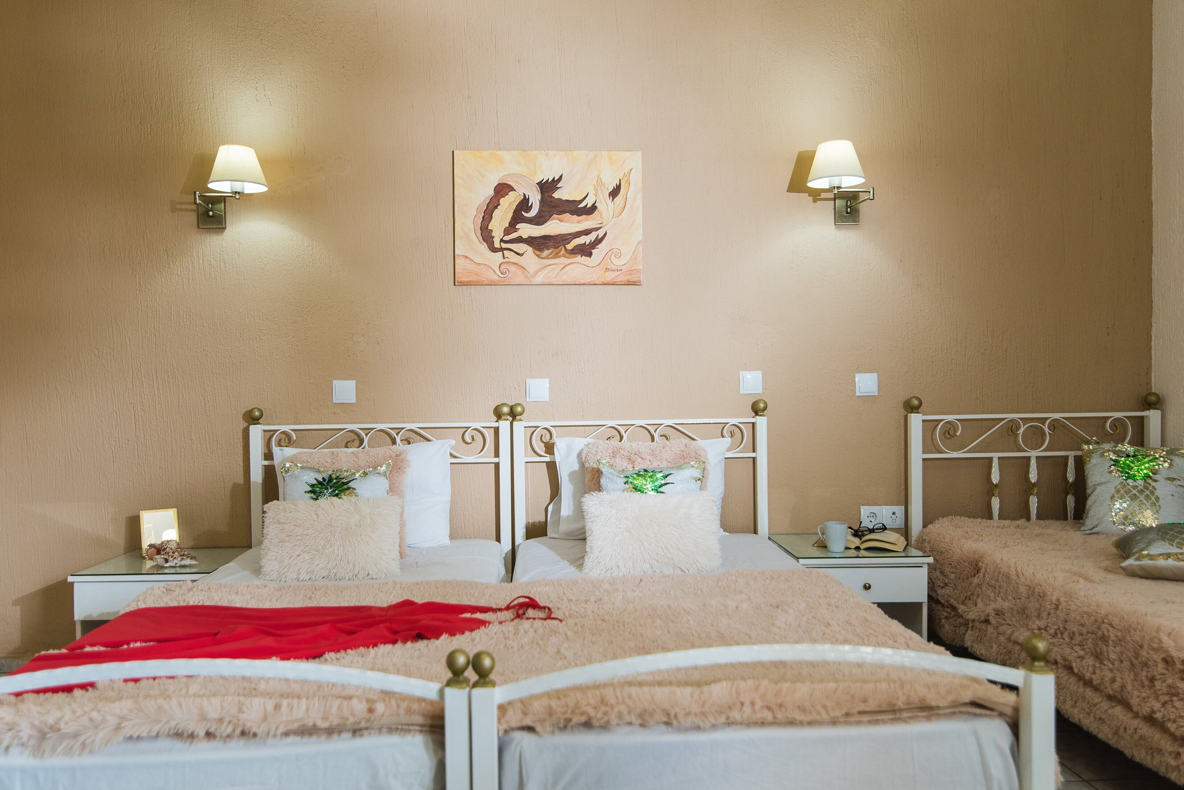 Ein Hotelzimmer mit zwei Betten, einem Bild an der Wand und zwei Wandleuchten.