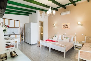 A bedroom with a white bed, a nightstand, a mirror, and a window. - Oasis Studios (Hersonissos)