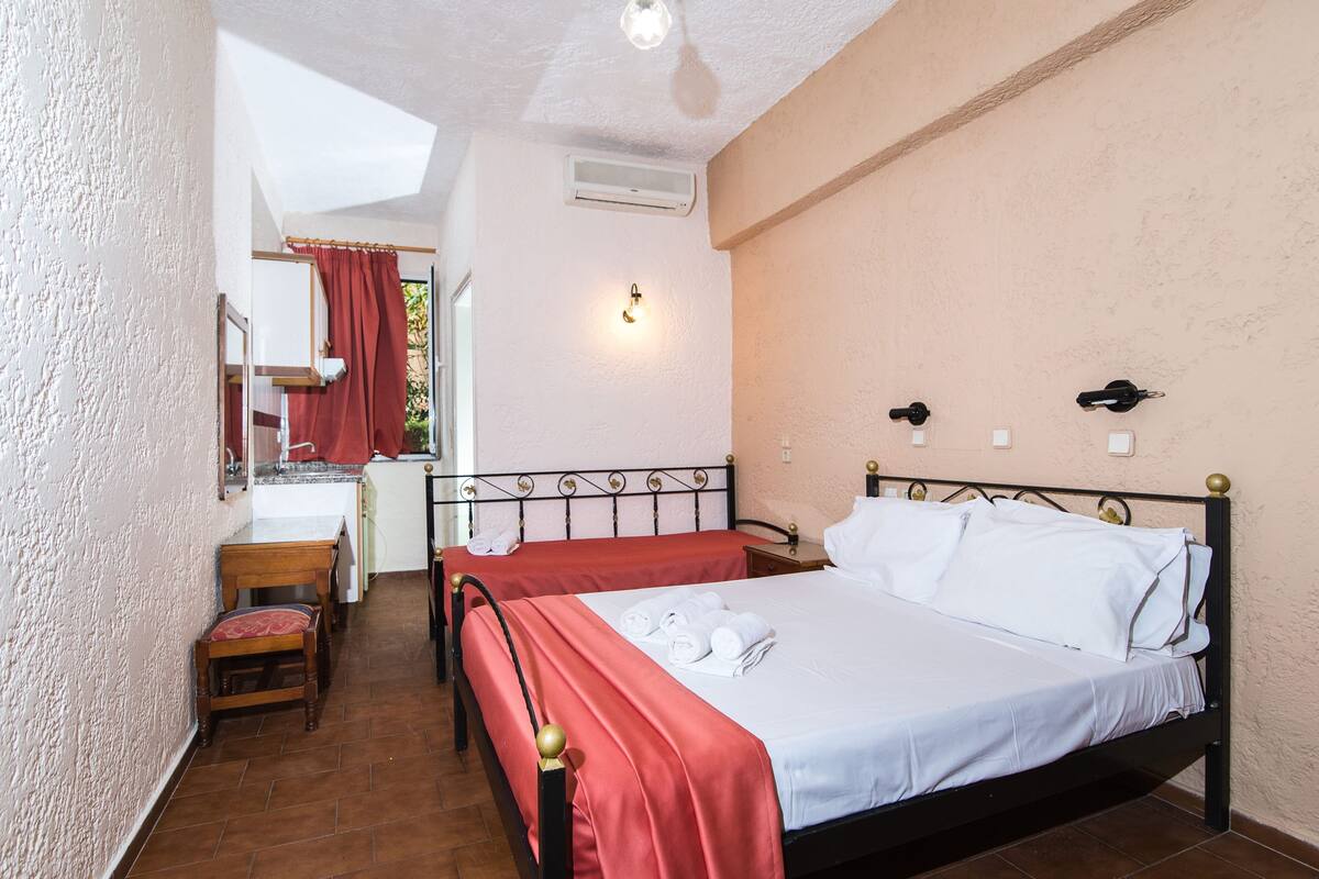 A hotel room with two beds, a small desk, and a bathroom visible through an open door.