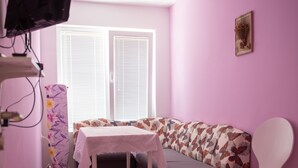 Une pièce avec un mur violet, un plancher en bois, un canapé, une table et une chaise.