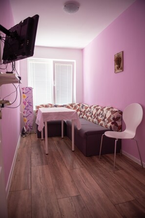 A room with a purple wall, a wooden floor, a sofa, a table, and a chair.