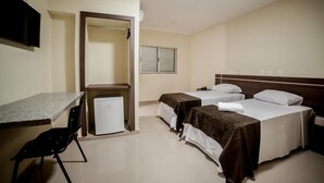 A hotel room with two beds, a desk, a chair, and a small refrigerator. - Apoema Hotel (Cuiabá)