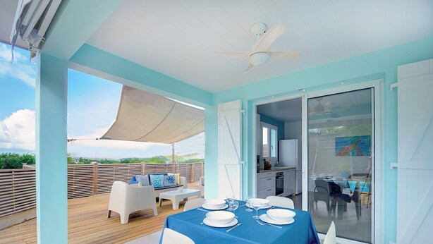 A dining area with a table set for four, a ceiling fan, and a view of the outdoors.