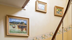 A staircase with a floral border, a vase of flowers, and two framed paintings on the wall. - Homerez - Apt. Saint-Martin-des-Entrées (Saint-Martin-des-Entrées)