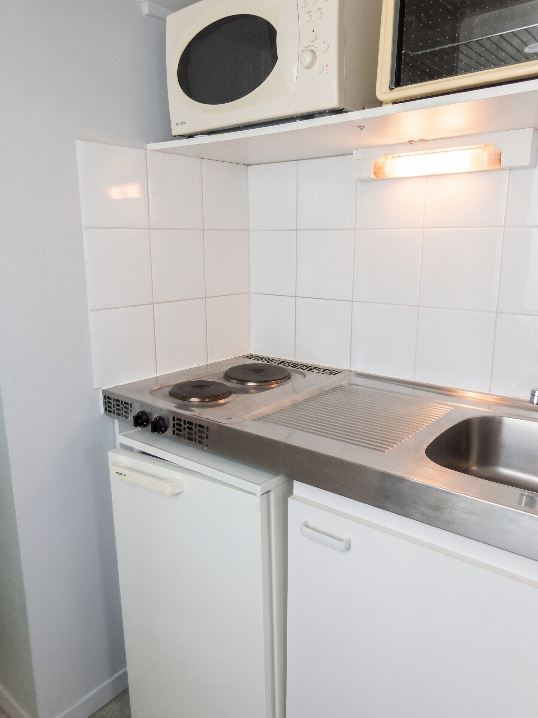 Una cocina compacta con microondas, estufa y lavabo.