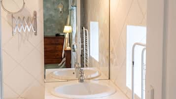 Een badkamer met twee wasbakken, een spiegel, toilet en handdoekrek.