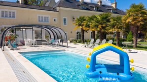 A swimming pool with a blue inflatable structure, lounge chairs, and a covered seating area. - Homerez - Apt. Saint-Martin-des-Entrées (Saint-Martin-des-Entrées)