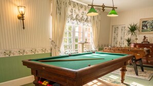 A pool table in a room with striped wallpaper, a green carpet, and a wooden dresser. - Homerez - Apt. Saint-Martin-des-Entrées (Saint-Martin-des-Entrées)