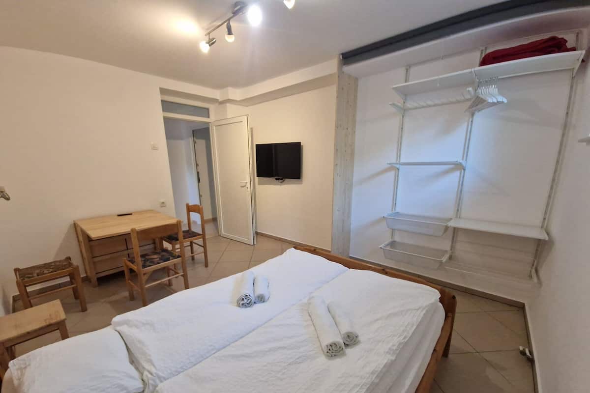 Ein Schlafzimmer mit einem Bett, einem Schreibtisch, einem Stuhl, einem Fernseher und einem Kleiderschrank.