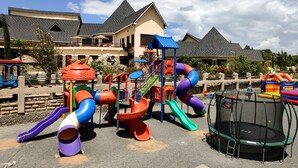 A playground with slides and climbing structures, surrounded by houses with sloped roofs. - Kiikaloh Grand Resort (Machakos)