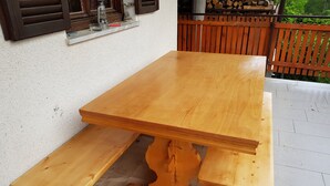 Een houten picknicktafel met een bank, op een betegeld terras.