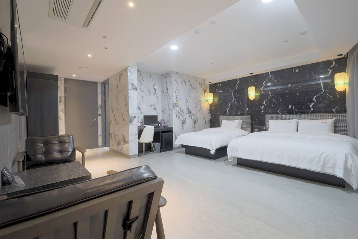 A modern hotel room with a large bed, a desk, and a seating area.