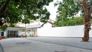 A hotel entrance with a paved area, a star-shaped symbol on the ground, and a white building with a visible entrance. - RedDoorz near Mataram University (Mataram)