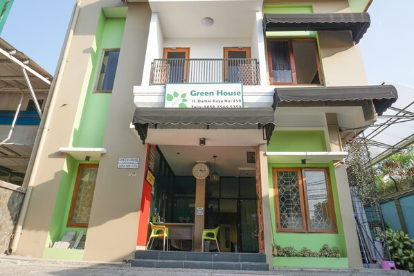 Un edificio de dos pisos con un letrero que dice "Green House" y un número de contacto.