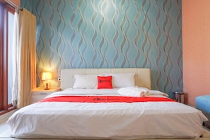 Une chambre d’hôtel avec un lit, une table de chevet avec une lampe et un mur décoré d’un motif.