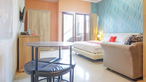 Een hotelkamer met een bed, een slaapbank, een tafeltje met stoelen, een kledingkast en een raam met gordijnen.