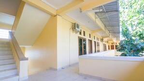 A corridor with a staircase, air conditioning units, and a plant.