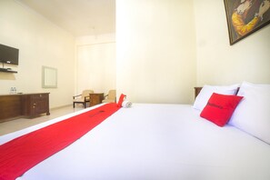 A hotel room with a large bed, a red throw blanket, a wooden desk, a chair, a television, and a painting on the wall. - RedDoorz near Nusa Cendana University (Kupang)