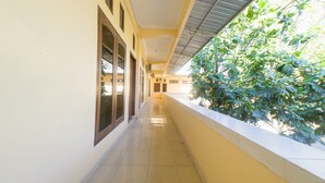 A corridor with a tiled floor, a yellow wall, and a window on the left.