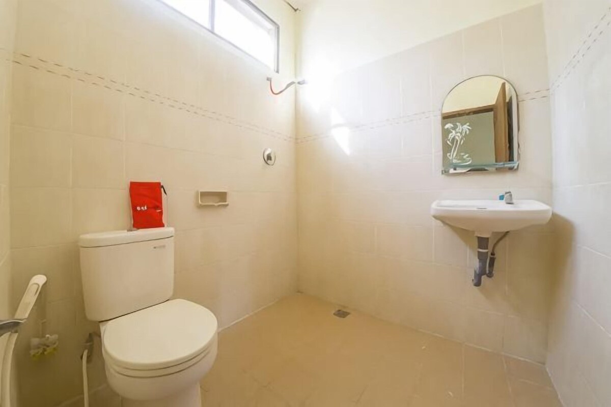 A small, clean bathroom with a toilet, sink, and mirror.