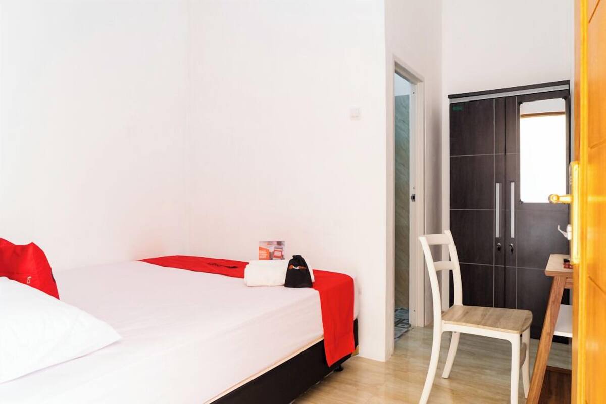 A bedroom with a bed, a chair, a wardrobe, and a door.