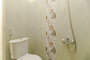A small bathroom with a toilet, a shower, and a wall-mounted towel rack. - RedDoorz near Tahura Berastagi (Berastagi)