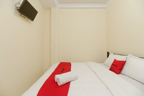 A hotel room with a bed, a red and white bedspread, a white towel, and a red pillow. - RedDoorz near Tahura Berastagi (Berastagi)