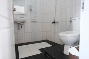 Une salle de bain avec un lavabo blanc, un miroir, une douche et des toilettes.