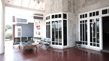 A spacious lobby with a marble floor, a glass-top coffee table, and metal chairs.