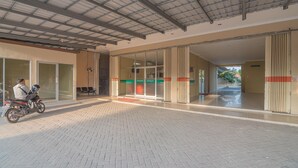 A covered entrance area with a tiled floor, glass doors, and a metal roof. - RedDoorz Plus near Syamsudin Noor Airport 3 (Banjarbaru)