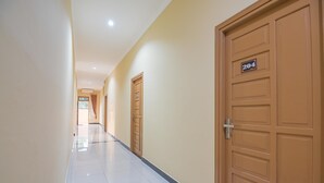 A hallway with doors, a number sign, and a tiled floor. - RedDoorz Plus near Syamsudin Noor Airport 3 (Banjarbaru)