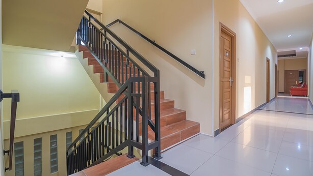 A staircase with black railings and wooden steps, leading to an upper floor. - RedDoorz Plus near Syamsudin Noor Airport 3 (Banjarbaru)
