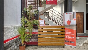 Letrero de RedDoorz que anuncia alojamiento económico, una escalera y plantas en macetas.