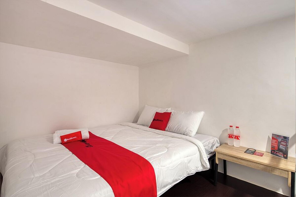 Ein Hotelzimmer mit Bett, Nachttisch und roter Decke.