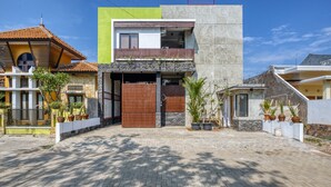 Una casa moderna con fachada de piedra, un balcón y un camino de entrada pavimentado.