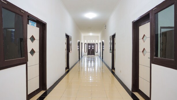 A corridor with doors on both sides, a tiled floor, and a ceiling light.