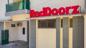 A building with a sign reading "RedDoorz" and a green gate.