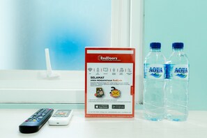 Un control remoto, un anuncio de RedDoorz y dos botellas de agua Aqua.