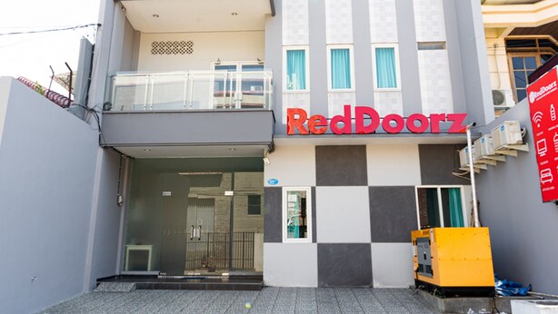 A building with a RedDoorz sign, a balcony, and a yellow moving staircase. - RedDoorz near Gajah Mada Street Semarang (Semarang)