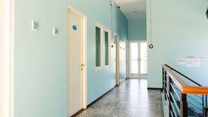 A hallway with light blue walls, white doors, and patterned floor tiles. - RedDoorz near Gajah Mada Street Semarang (Semarang)