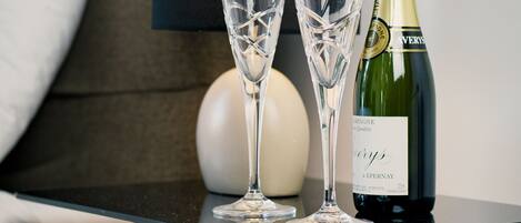 A neatly arranged table with two champagne flutes and a bottle of champagne in a hotel room.
