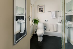 Un baño moderno con inodoro blanco, lavabo y espejo.
