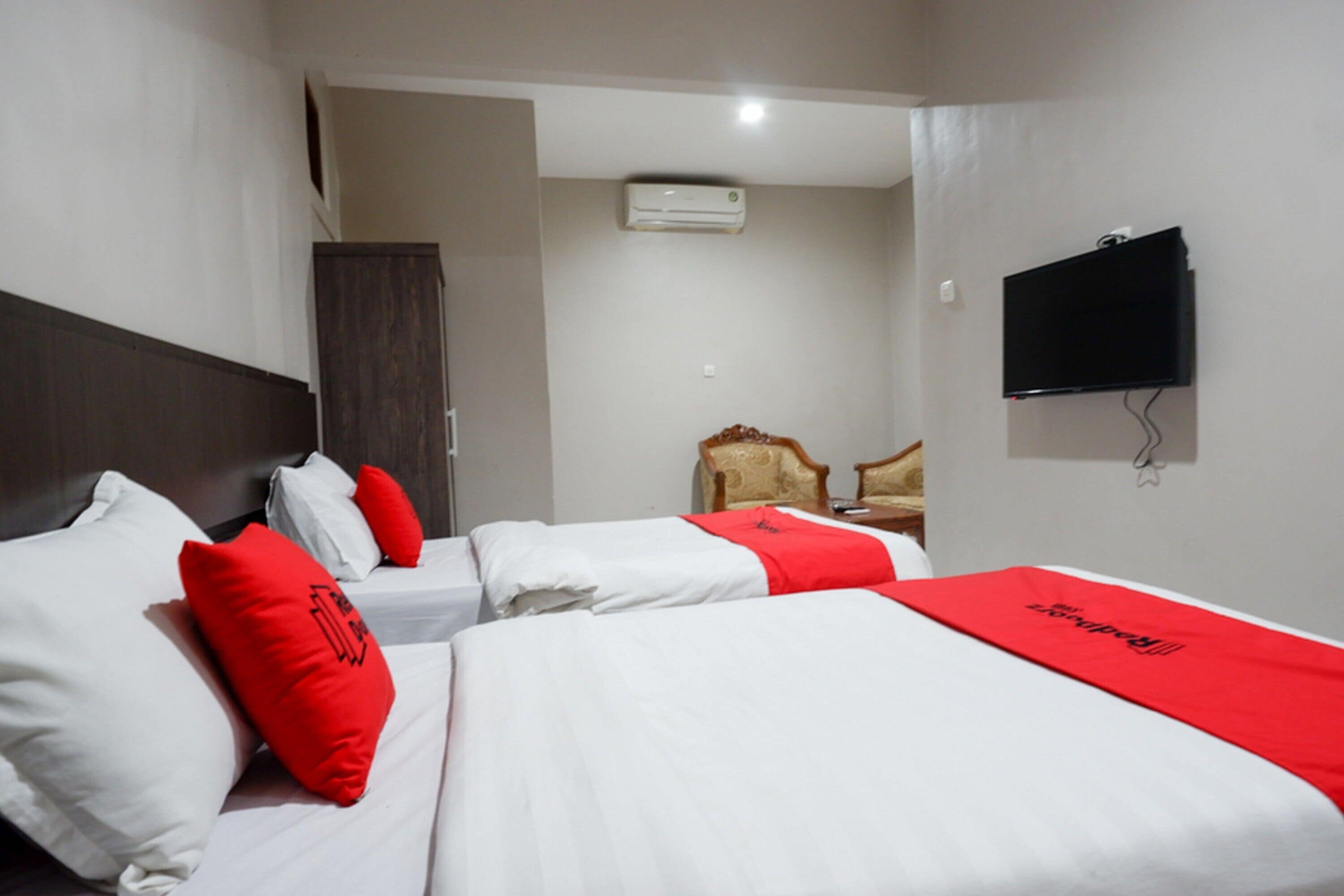 Ein Hotelzimmer mit zwei Betten, einem Fernseher, einer Klimaanlage und einem Kleiderschrank.