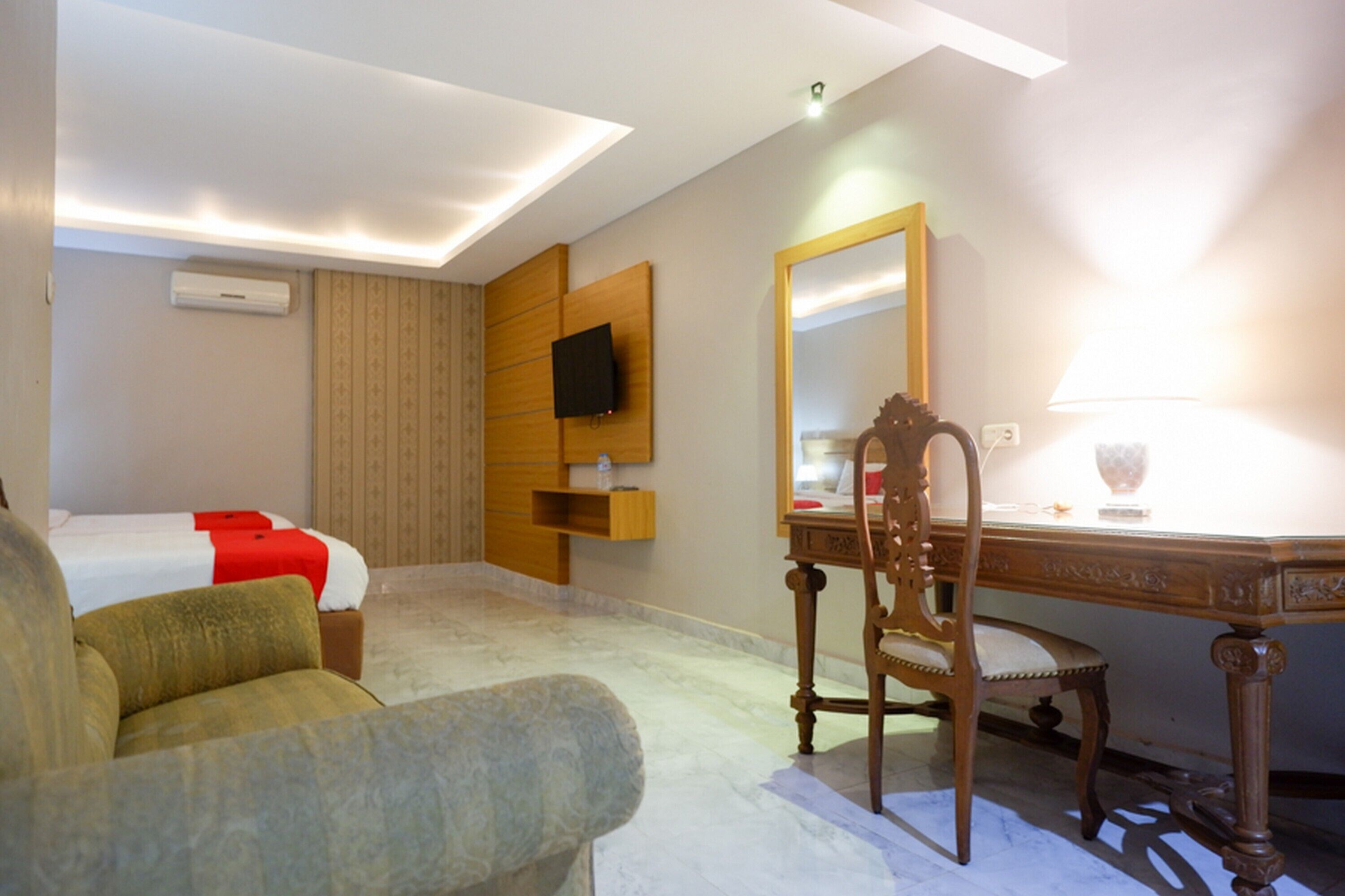 A hotel room with a bed, a desk, a chair, a television, and a mirror.