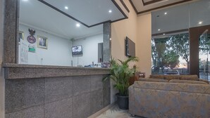 A reception area with a stone counter, a television, a framed picture, and a sofa. - RedDoorz near Alun Alun Subang (Subang)