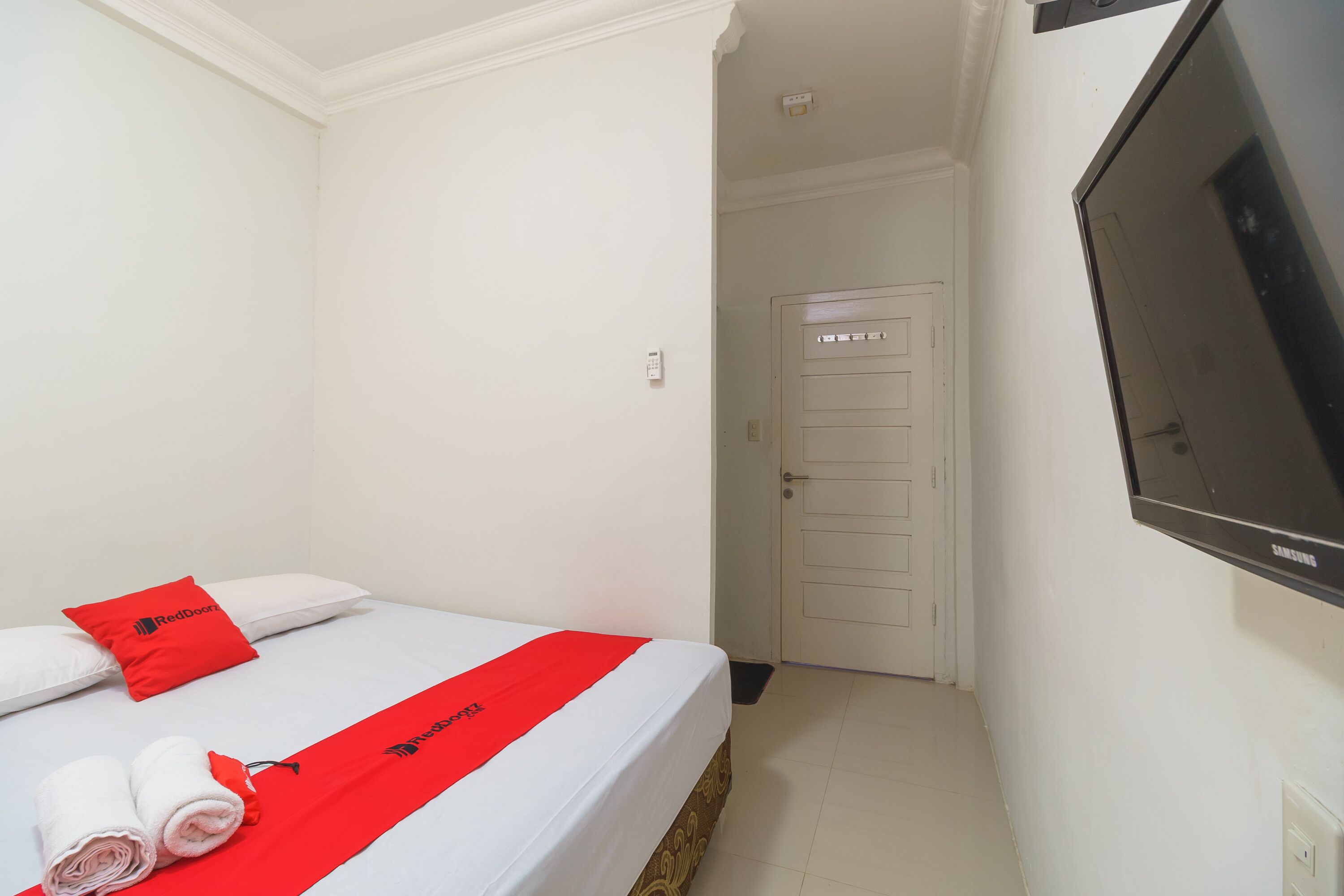 Quarto de hotel com uma cama, televisão e porta.