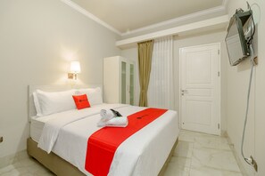 A hotel room with a bed, a nightstand, a lamp, a wardrobe, and a door.