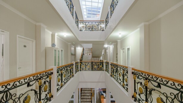 Ein geräumiger Innenraum mit einer zentralen Treppe, einem Oberlicht und Blick zum oberen Stockwerk.