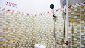 Ein Badezimmer mit gefliestem Boden und Wänden, einer Toilette und einem Duschbereich mit Brausekopf.
